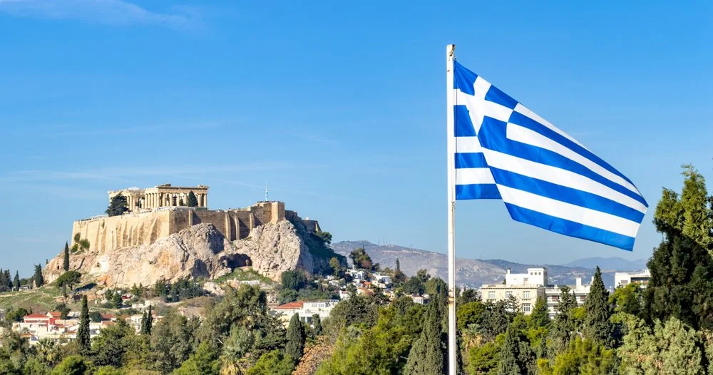 The Greek Tax Incentives Putting Greece on the Radar of Wealthy British Households The Acropolis of Athens beneath a Greek flag, the capital at the centre of Greece's tax incentives for new residents