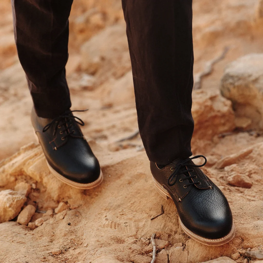 Black leather Joseph Cheaney derby boots worn on dry stone ground Black leather Joseph Cheaney derby boots worn on dry stone ground