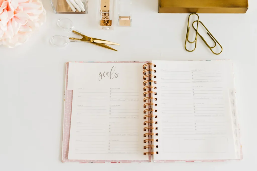 How to Make Difficult Tasks Feel Less Overwhelming Open goals planner on a tidy desk with gold stationery
