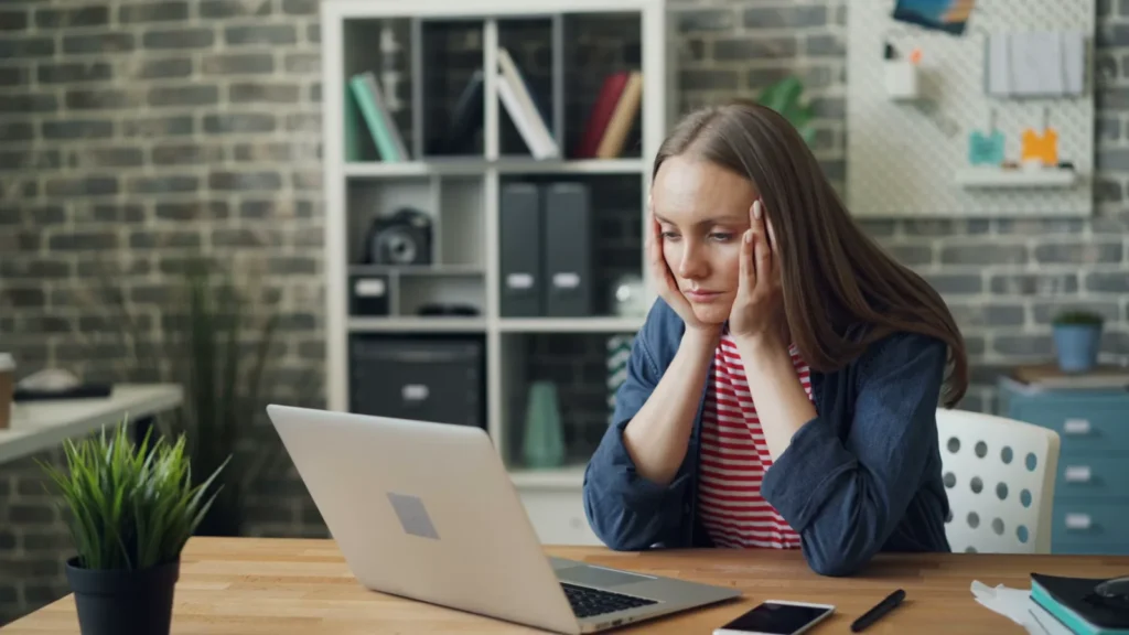 How to Make Difficult Tasks Feel Less Overwhelming Woman looking overwhelmed at her laptop in a home office